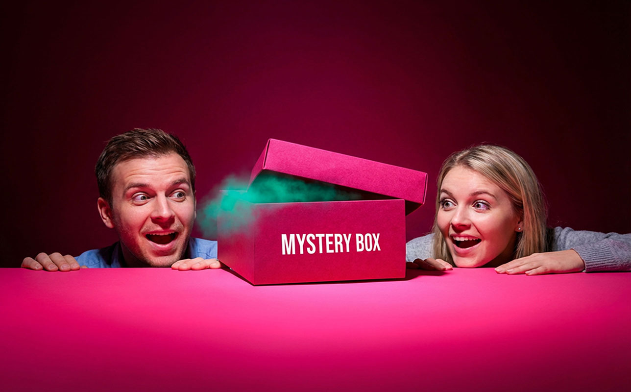 Egy férfi és egy nő várják izgatottan, hogy kinyíljon a Mystery Box, amiben a rendelt ivós játékaik vannak. A Mystery Box termékkategóriára linkel a banner és a gomb.
